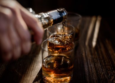 pouring-strong-alcohol-drink-into-glasses-which-are-wooden-table(1)